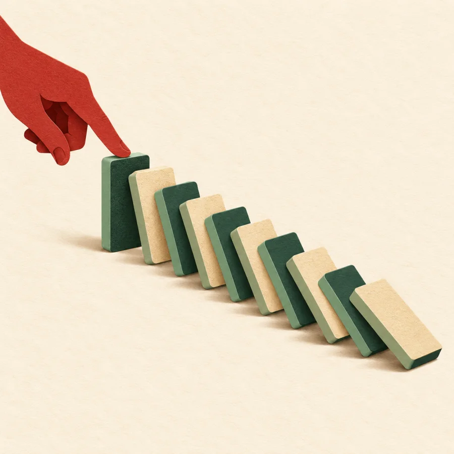 A hand tips the first domino tile, toppling the whole row in sequence