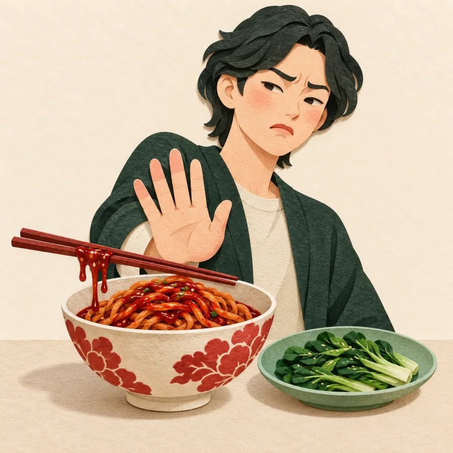 A person pushes away a bowl of noodles glistening with thick red sauce
