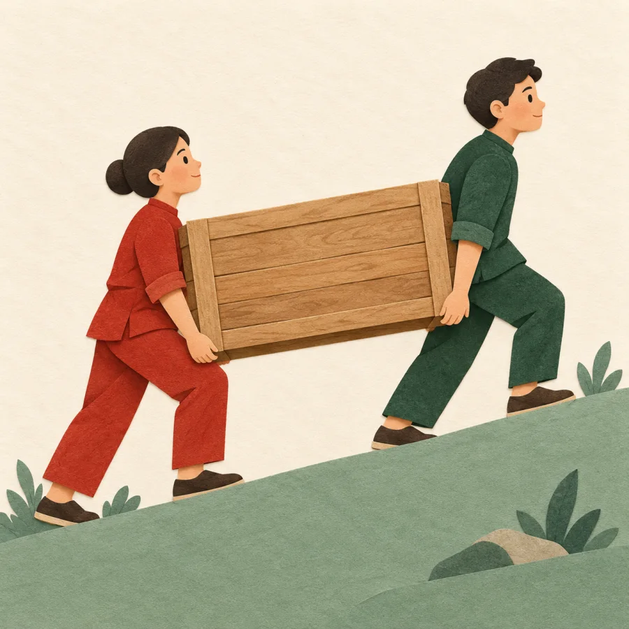 Two people carrying a heavy crate together uphill