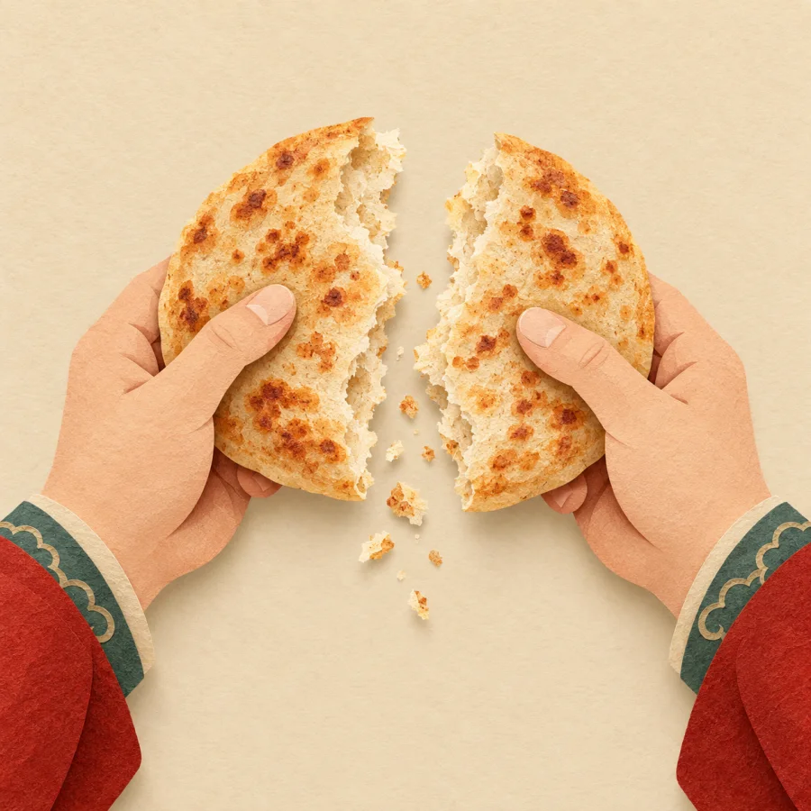 Two hands break a round flatbread in half