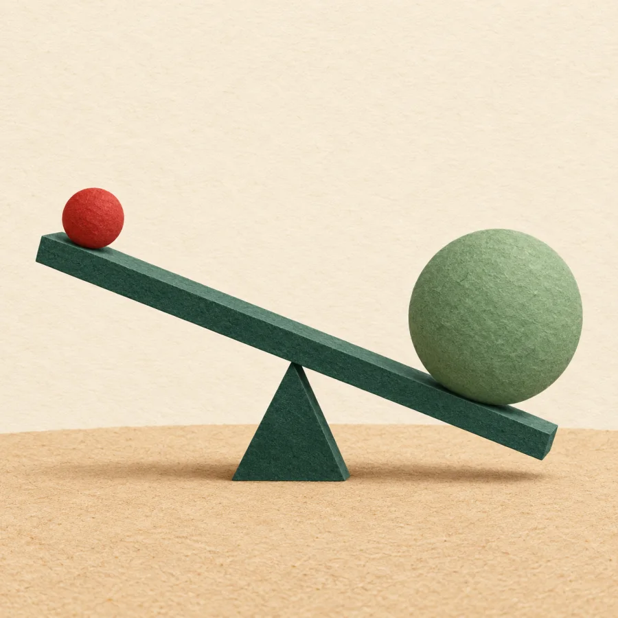 A seesaw with a small red ball up and a large green one down