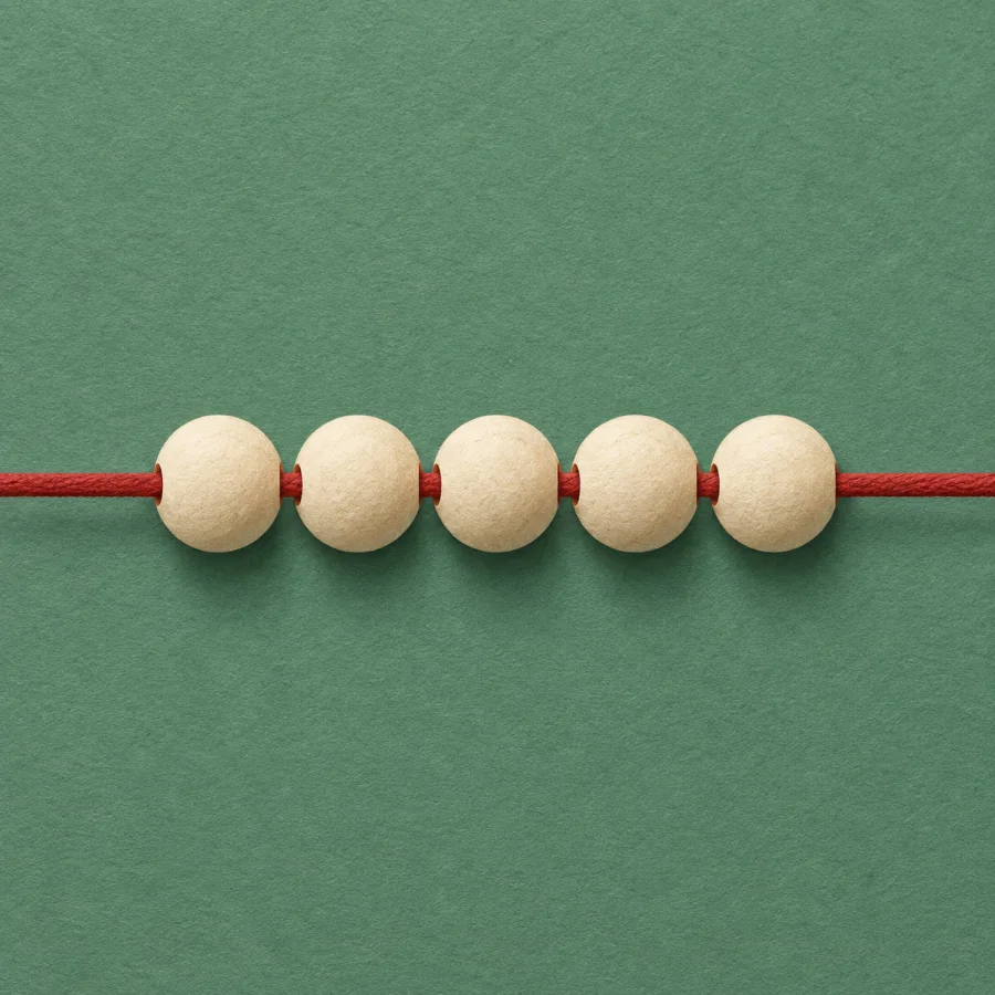 A red thread runs through a row of cream beads