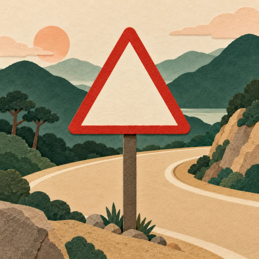 A red triangular sign beside a sharp road curve