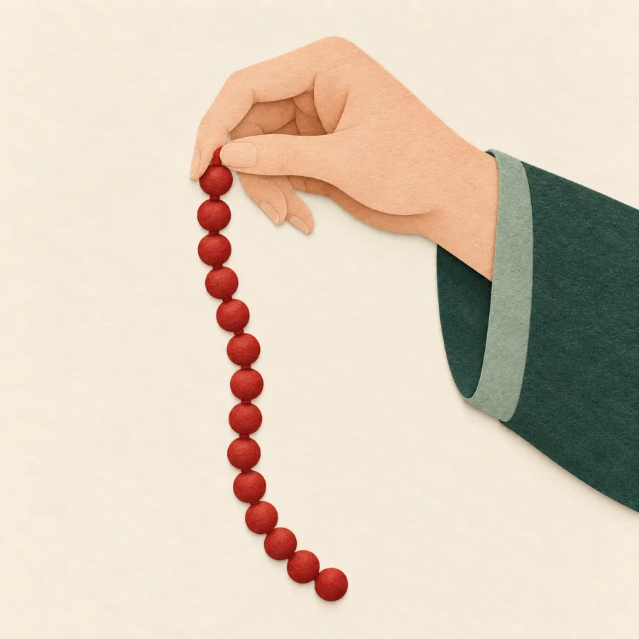 A hand holds a string of red beads with no gaps