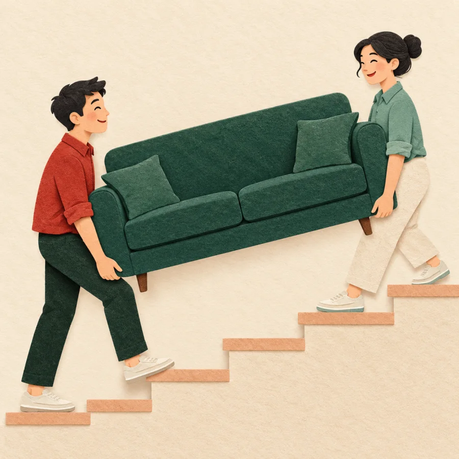 Two people carrying a sofa up the stairs in step