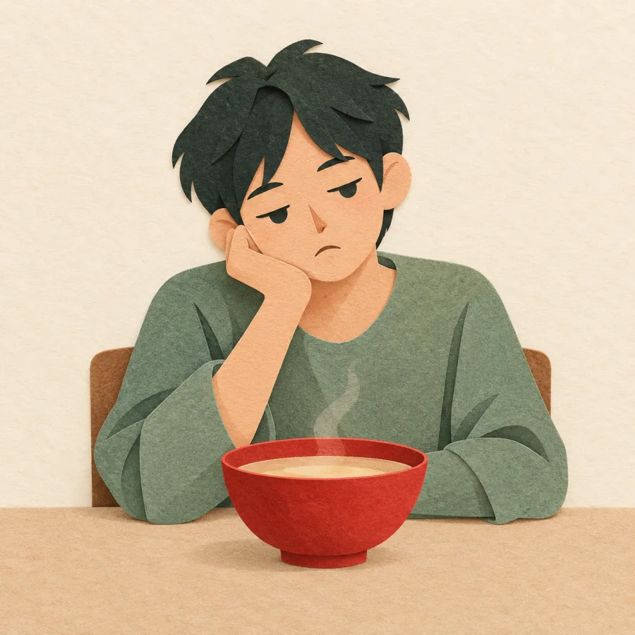 A bored person rests their chin over a plain bowl of soup