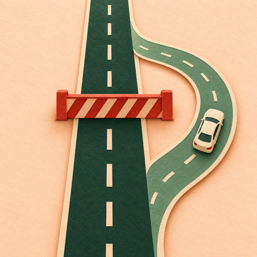 A cream car drives around a red barrier on a side path